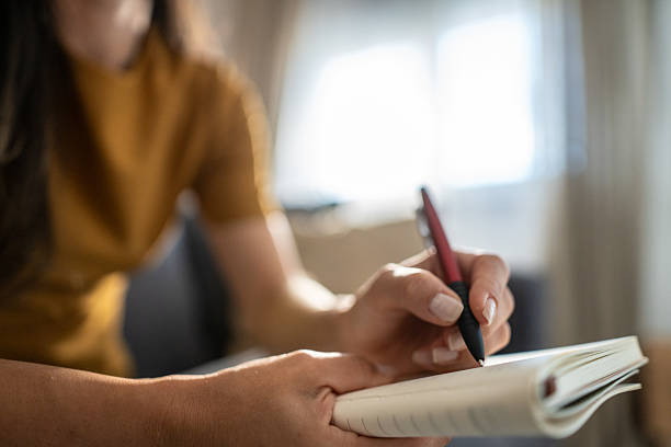 istock Woman writing notes in a small journal at home 2239327232