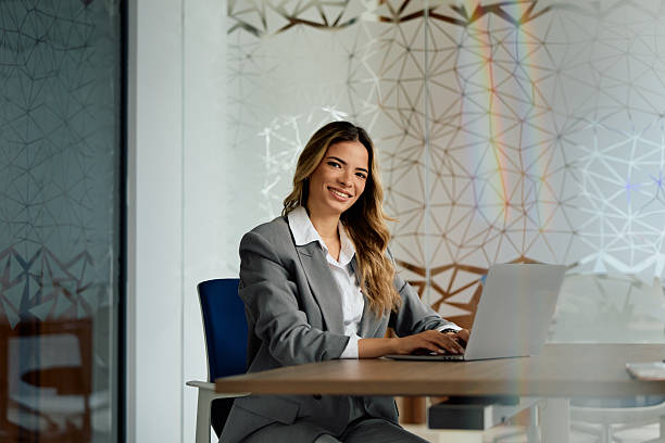 istock Businesswoman smiling while working on laptop in modern office 2239329447