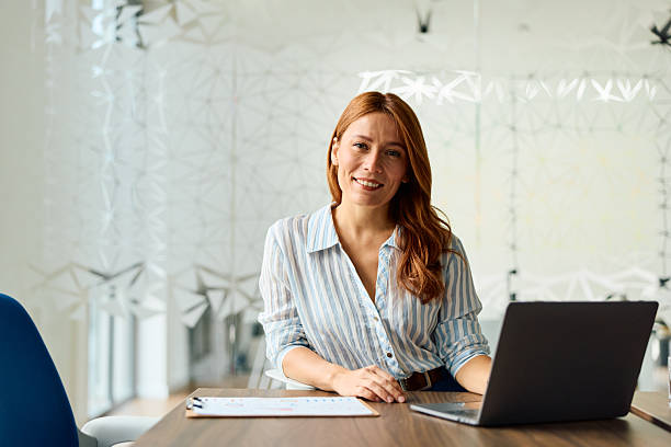 istock Professional businesswoman smiling while working on laptop 2239333563