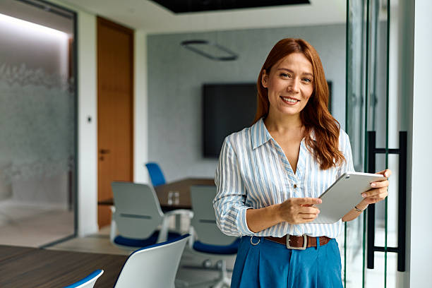 istock Professional woman standing in office holding tablet smiling 2239333578