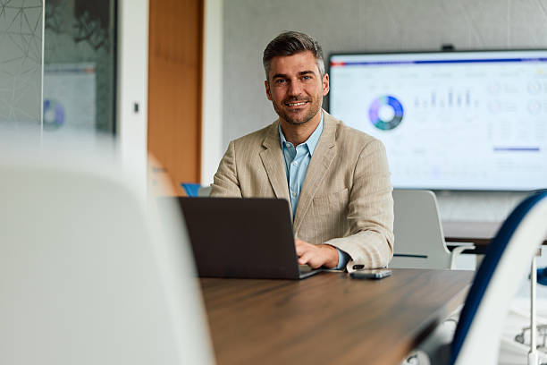 istock Businessman smiling in modern office using laptop 2239333752