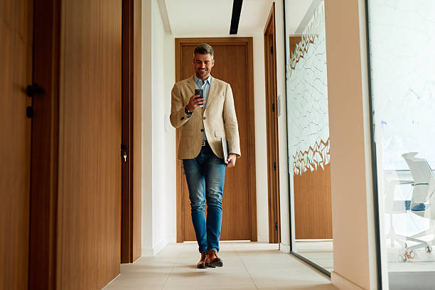 istock Professional man walking in office hallway using smartphone 2239333912