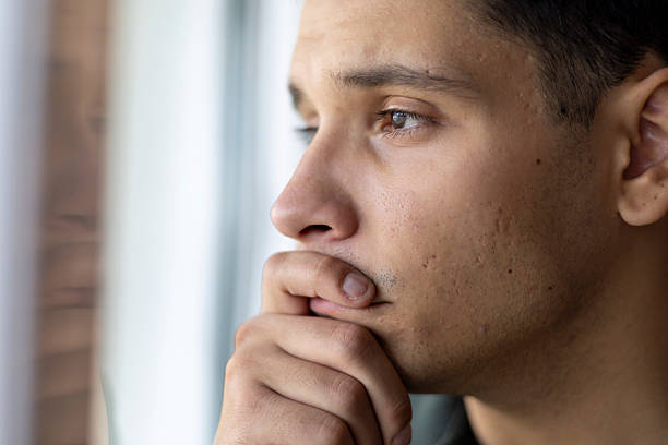 istock Young man thinking or worrying, feeling pensive and looking out of a window 2239333950