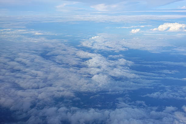 Beautiful white clouds drifting peacefully in the blue sky as seen from above or Layers of soft clouds stretching across the sky during a daytime flight.