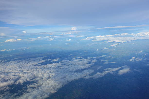 Beautiful white clouds drifting peacefully in the blue sky as seen from above or Layers of soft clouds stretching across the sky during a daytime flight.