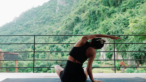 istock Rear view of a woman practicing a side bend yoga pose on the mat 2239353921