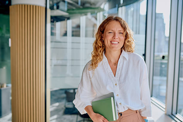 istock Businesswoman standing in modern office holding notebook 2239358494