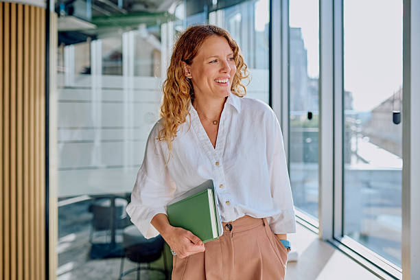 istock Confident businesswoman smiling and holding a notebook in office 2239358519