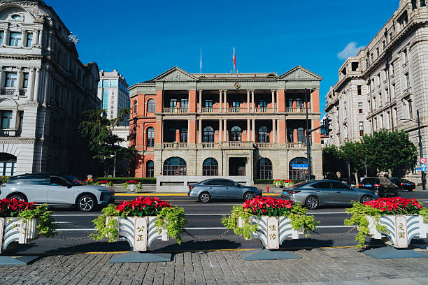 Shanghai, China - September 24, 2025: A vibrant streetscape featuring classic architecture, blooming flower planters, and bustling traffic in the historic Bund area.