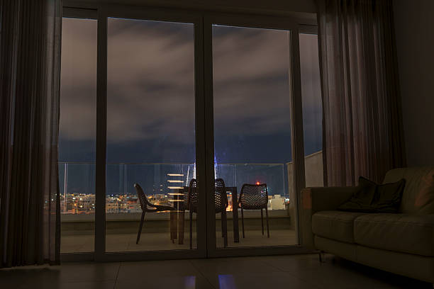 istock Night City View Through Glass Doors to Cozy Balcony Seating 2239367700