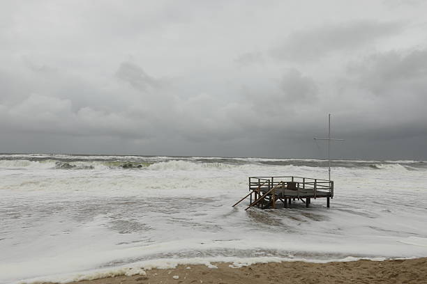 Long foamy waves with a kite surfer in a distance on a cloudy and windy day.