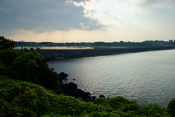 A sheltered inlet at Hado Beach reflects the sky as a long stone causeway protects the shallow bay on Jeju's northeastern shore.