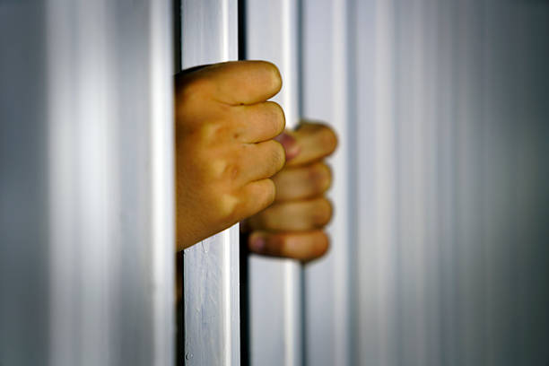 istock Hands Gripping Bars Symbolizing Confinement and Isolation 2239376707