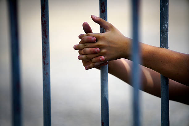 istock Hands Gripping Metal Bars Symbolizing Confinement and Restriction 2239376875