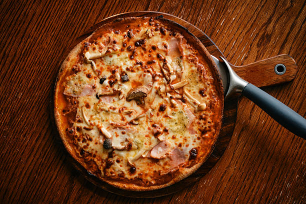 Assorted Pizza on Wooden Board with Bacon, Mushrooms, Pepperoni, and Four Cheeses - Top View.