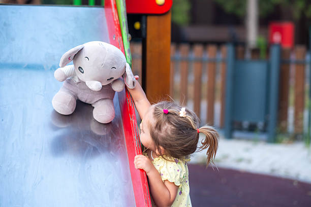 istock Toddler girl playing with stuffed elephant on slide 2239377415