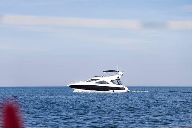 A sleek white luxury yacht sails across a tranquil blue ocean with a bright day sky, evoking leisure, travel, and premium boating lifestyle.