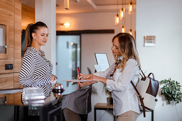 istock Receptionist assists guest at modern hotel front desk during busy check-in process 2239382577