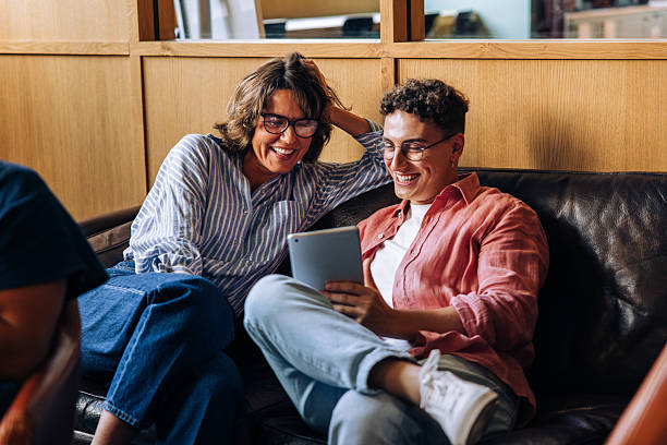 istock Middle-aged woman and young man enjoying tablet together on a sofa 2239382801