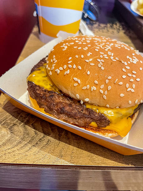 istock Appetizing cheeseburger with grilled beef patty, melted cheese, sesame bun, served in a paper tray, representing quick, satisfying fast-food dining 2239389528