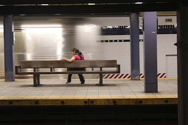 Queens, New York.  Taken Sept 9, 2012. Subway Train  station in Queens - a woman is sitting in the seat at the station while the train passes by in Queens, New York City.