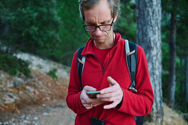istock Hiker With Red Jacket Using Smartphone In Forest Trail, Outdoor Adventure, Backpack, Nature Setting 2239401029