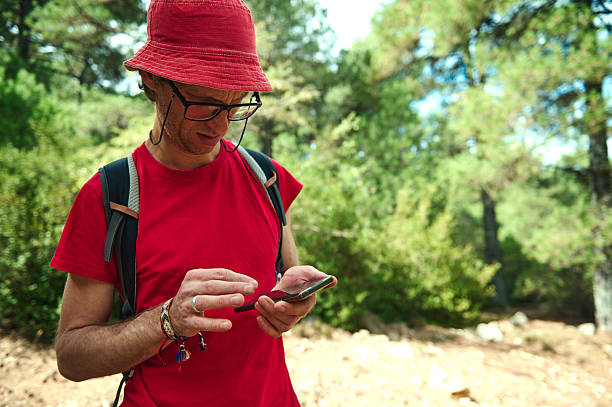 istock Man In Red Shirt With Hat Using Smartphone On Forest Trail 2239401112