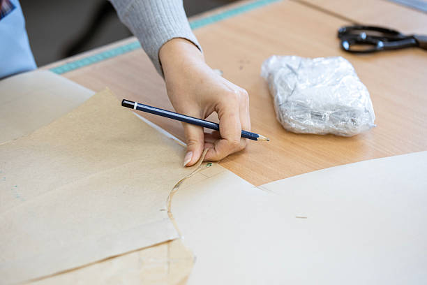 istock A fashion designer, cutter, or dressmaker working with paper sewing patterns on a large table. A concept of the creative process and handmade clothing design. 2239402511