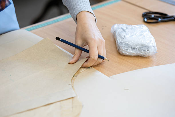 istock A fashion designer, cutter, or dressmaker working with paper sewing patterns on a large table. A concept of the creative process and handmade clothing design. 2239402516
