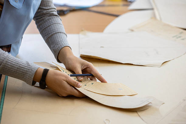 istock A fashion designer, cutter, or dressmaker working with paper sewing patterns on a large table. A concept of the creative process and handmade clothing design. 2239402539