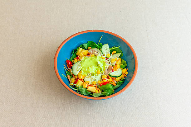 A blue bowl with a vegetable salad with sauce