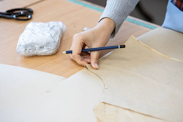 istock A fashion designer, cutter, or dressmaker working with paper sewing patterns on a large table. A concept of the creative process and handmade clothing design. 2239405001