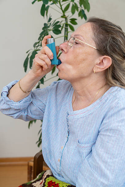 istock Senior Woman Using Asthma Inhaler While Sitting on Couch. 2239405036