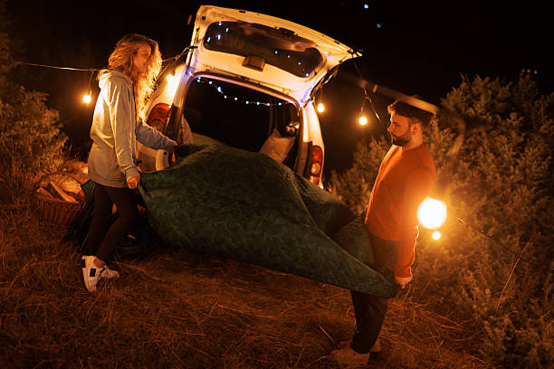 istock Couple setting up a cozy sleeping area in the back of their car under string lights during a night camping trip in a forest 2239405102