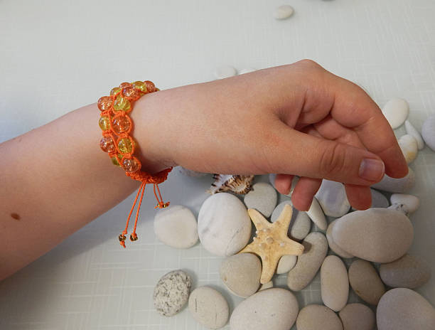 istock Handmade orange beaded bracelet on a beach-themed setting 2239405316