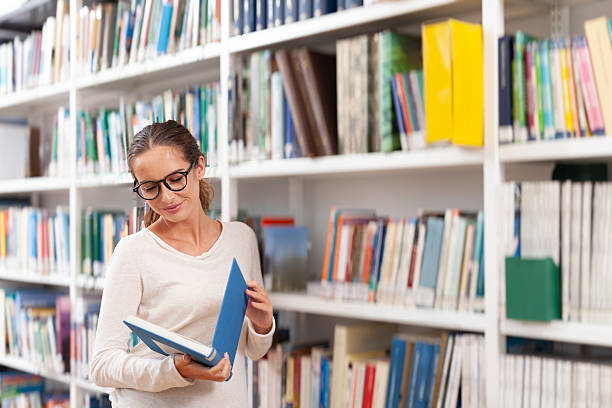 istock Young woman reading a book in a modern library 2239405477
