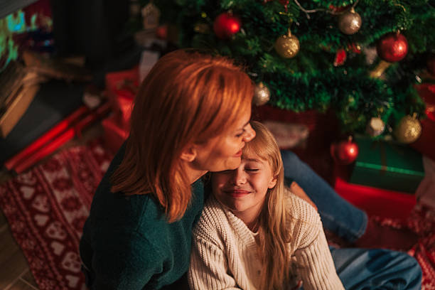 Mother and daughter embracing under christmas tree
