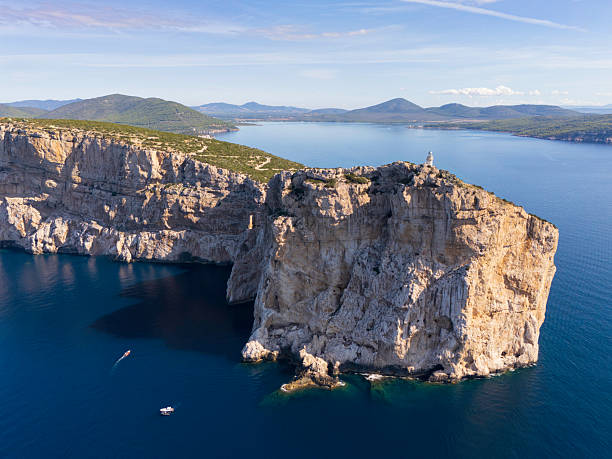 istock A dramatic coastal cliff island with a lighthouse, blue sea, and distant hills 2239418630
