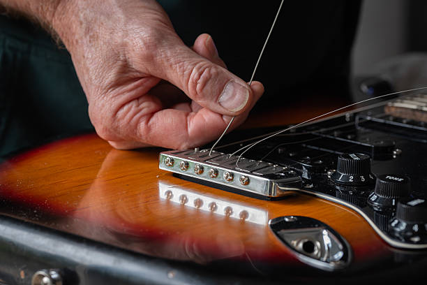 istock Inserting a new guitar string through the bridge of an electric guitar 2239420434