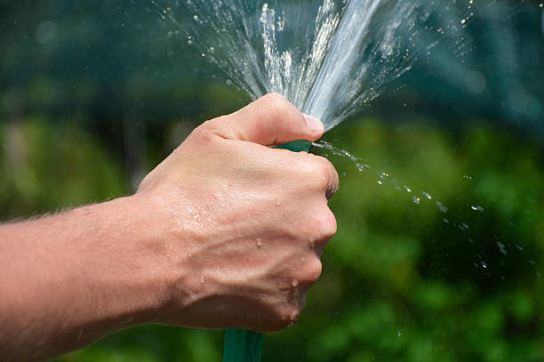 istock A man's hand holds a watering hose and closes the hole with his thumb 2239431177