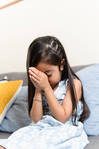 istock Girl praying with hands clasped in thoughtful innocence 2239440927