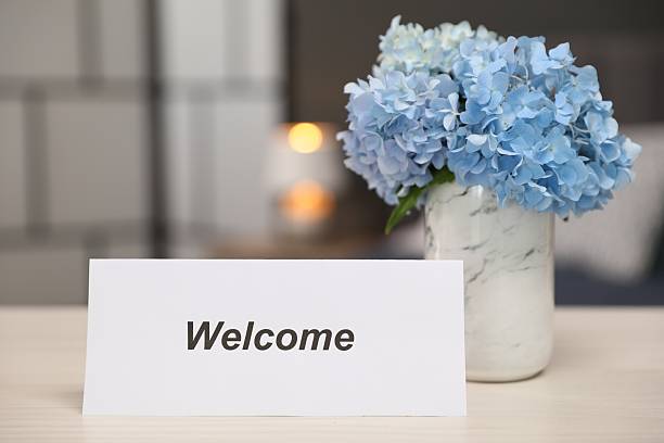istock Card with word Welcome and hydrangea flowers on wooden table, closeup 2239443231