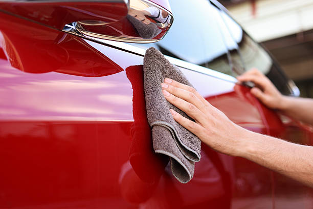 istock Man wiping car with grey microfiber rag outdoors, closeup 2239445020