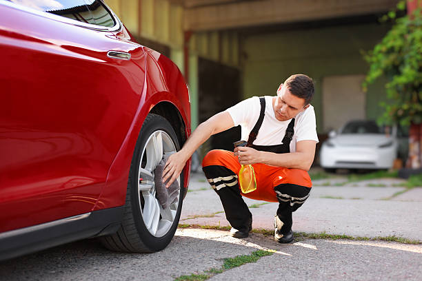 istock Man wiping car wheel with grey microfiber rag outdoors 2239445186