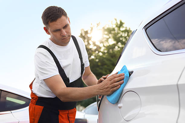 istock Man wiping car with blue microfiber rag outdoors 2239445210