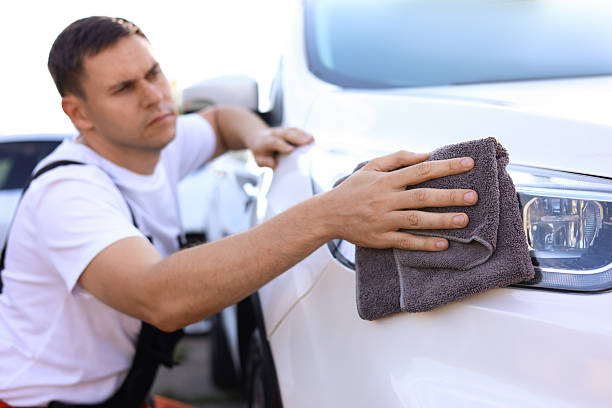 istock Man wiping car headlight with grey microfiber rag outdoors, closeup 2239445229