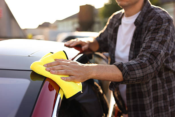 istock Man wiping car with yellow microfiber rag outdoors, closeup 2239445251