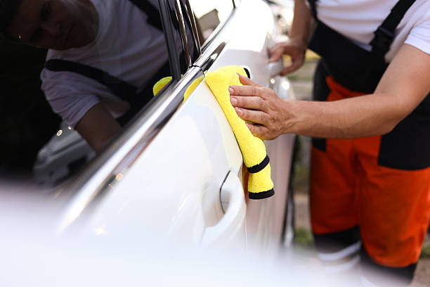istock Man wiping car with yellow microfiber rag outdoors, closeup 2239445329