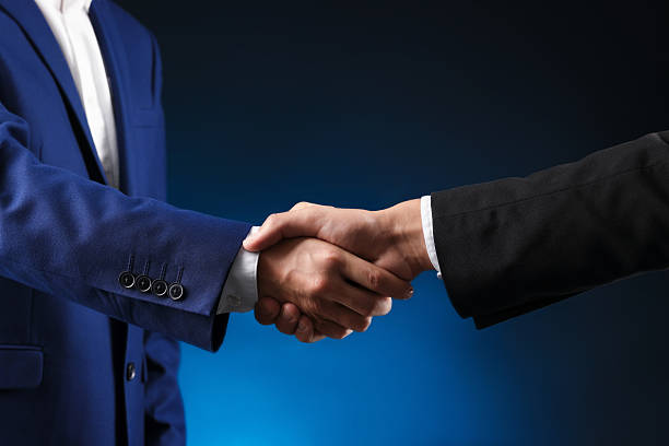 istock Business partners shaking hands on dark blue background, closeup 2239446425