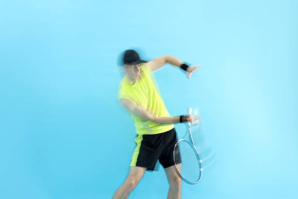 Man with racket playing tennis on light blue background, motion blur effect